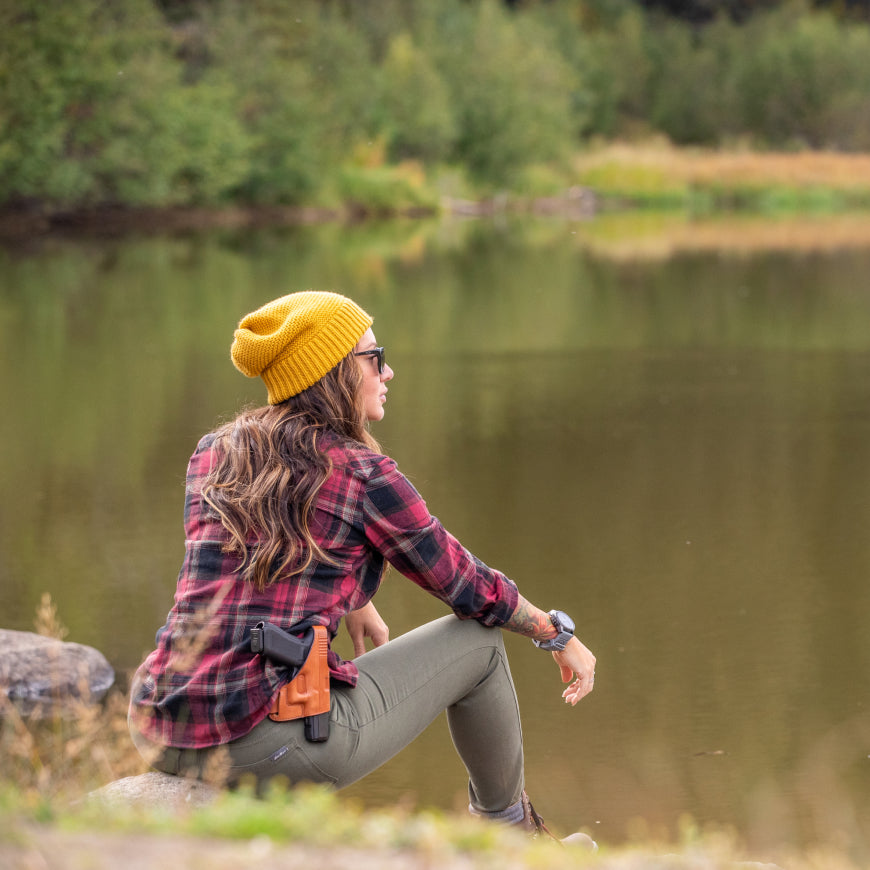 woman wearing leather outside waistband holster sitting by lake